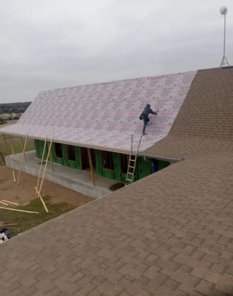 Worker preparing underlayment for a metal roof installation in Murray